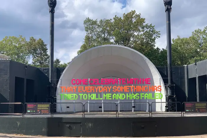 Bright big multicolored letters in front of the Prospect Park Bandshell spell out a message about triumphing over death.